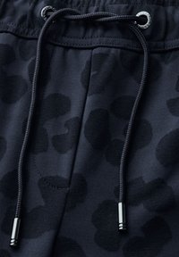 Joggers navy avec un motif léopard noir discret. Caracterisé par un cordon de serrage avec des embouts en métal et un tissu texturé. Conception douce et ajustée.