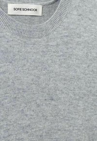Pulover gri cu guler rotund, prezentând un tricot moale, texturat. Eticheta scrie "SOFIE SCHNOOR" și se află la guler.