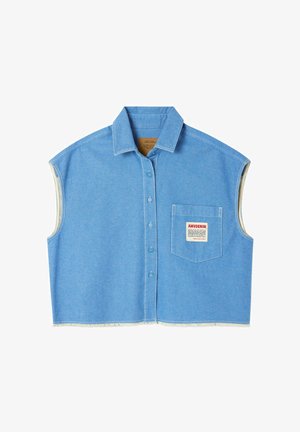 Mouwloos lichtblauw denimshirt met knoopsluiting aan de voorkant, spreadkraag, borstzak met rood-zwarte AMVDENIM tekstlabel en onafgewerkte zoomranden.