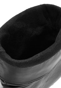 Czarne skórzane buty z miękkim, teksturowanym wnętrzem. Zaokrąglony górny brzeg i gładki zewnętrzny, z przeszyciami wzdłuż boków.