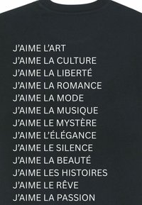 T-shirt noir avec texte imprimé blanc. Le texte énumère diverses phrases en français exprimant l'amour pour l'art, la culture, la liberté, et plus encore.