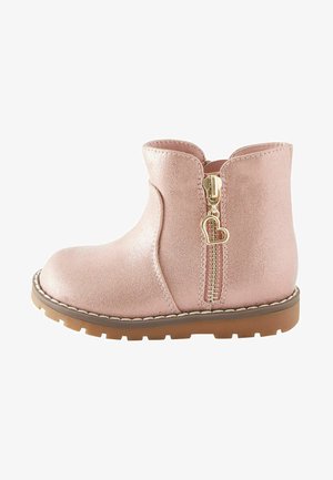 Rožinė metalinė kulkšnine bota su apvaliu pirštu, šoniniu užtrauktuku, kuriame yra širdelės formos traukimo detalė, ir tekstūruota paviršiumi ant rudos gumos pado.