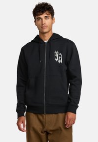 Black zip-up hoodie made of cotton blend, featuring a front pocket and a graphic logo in white on the left chest. Smooth texture, casual fit.