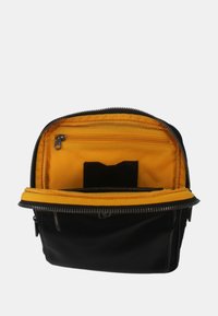 Borsa nera con un interno giallo, dotata di una tasca con zip e di un vano. Esterno testurizzato con una forma strutturata. Chiusura con zip.