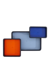 Set of three square trays in orange, light blue, and dark blue. Each has a smooth surface with rounded edges and a textured black border.