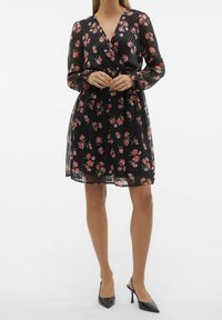 Svart blommig klänning med långa genomskinliga ärmar, V-ringning, elastisk midja och längd över knäet som har rosa och röda blommönster.