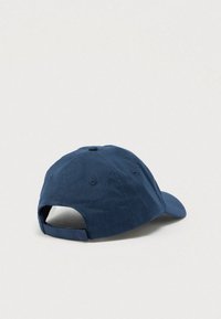 Navy blue adjustable baseball cap resting on a light surface, shown from the back with visible strap and ventilation eyelets.