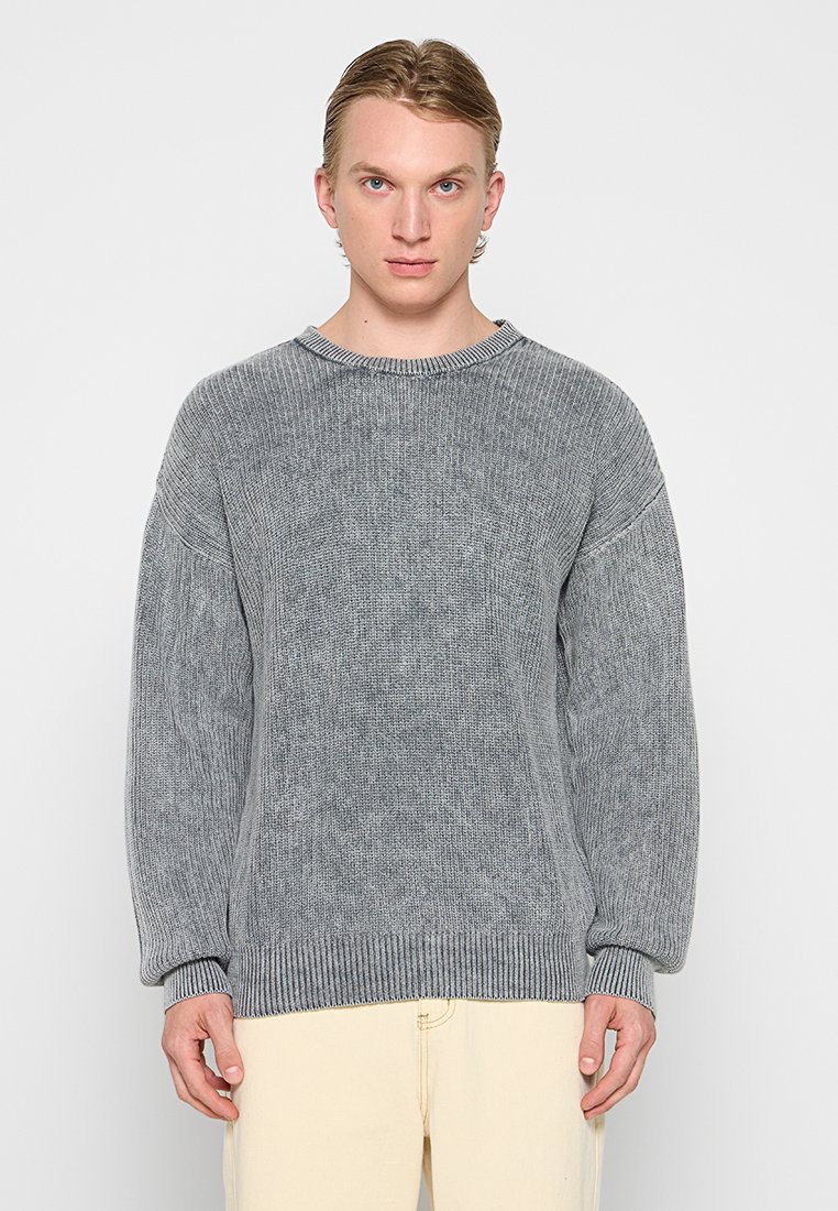 Grijze gebreide trui met een ronde halslijn, verlaagde schouders en geribbelde boorden en onderrand. Gemaakt van gestructureerde stof, met een losse pasvorm.