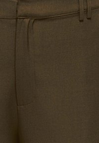 Primer plano de pantalones verde oliva mostrando la pretina frontal, las trabillas para cinturón y las costuras del bolsillo en tela texturizada.