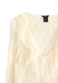 Blusa di pizzo color crema con scollo a V arricciato e maniche lunghe, etichettata taglia S e prodotta in Turchia.