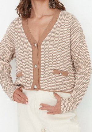Bruine en crème gebreide cardigan met een V-hals, knoopsluiting, twee voorzakken en parelachtige accenten op de knopen. Zachte breiatekstuur.