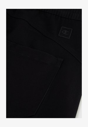 Shorts de sport noirs avec une texture lisse, dotés d'une poche arrière et d'un petit logo en relief. Taille élastique pour plus de confort.