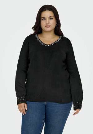 Maglione nero con scollo a V, decorato con borchie argentate attorno al colletto e sui polsini. Tessuto morbido con orlo a coste.