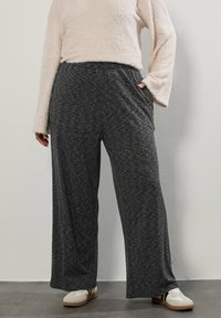 Szare, szerokie spodnie z fakturowanej tkaniny i elastycznym paskiem w talii, z bocznymi kieszeniami. Połączone z lekką, puszystą bluzką z długimi rękawami.