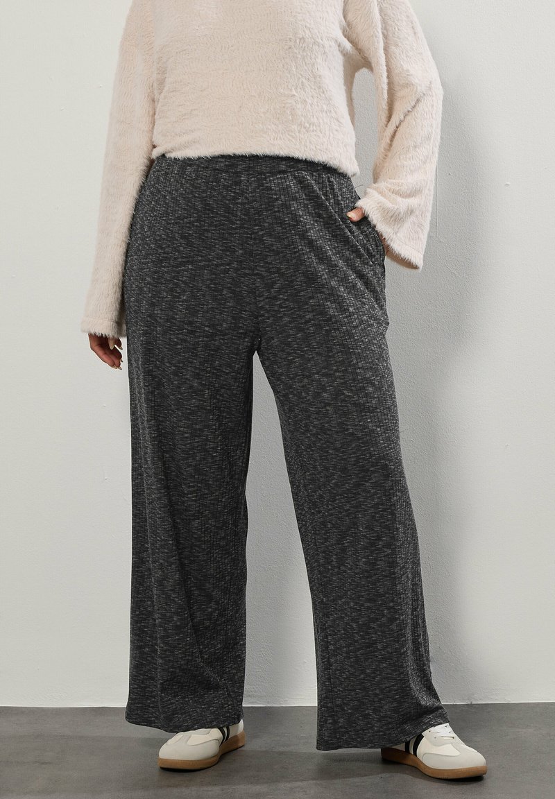 Szare, szerokie spodnie z fakturowanej tkaniny i elastycznym paskiem w talii, z bocznymi kieszeniami. Połączone z lekką, puszystą bluzką z długimi rękawami.