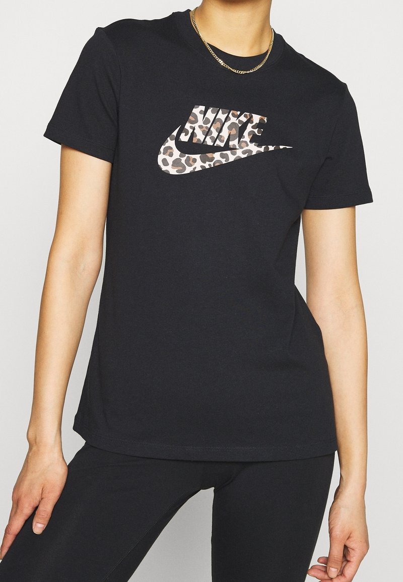 Svart bomull t-shirt med ett leopardmönstrat Nike-logo. Korta ärmar, rundad hals och en figurnära silhuett. Slät textur.