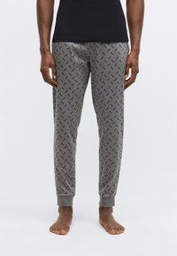 Szürke pizsamanadrág, fekete geometriai mintával ismétlődve, rugalmas derékrésszel és bokánál húzott szegéllyel. Puha, sima anyagból.