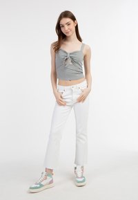 Grå ribbet crop top med knyttet for-Detalje, parret med hvide straight-leg jeans og multicolore høje sneakers.