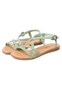 Sandalias de ante verde con múltiples tiras cruzadas, correa ajustable en el tobillo y una suela de goma marrón claro. Diseño plano para mayor comodidad.