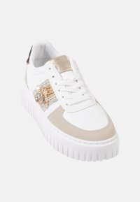Baskets blanches avec accents beiges, détails texturés en or et argent, bout arrondi et semelle épaisse en caoutchouc blanc. Lacets et col rembourré présents.