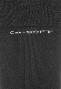 Schwarze, gerippte Socken mit einer weichen Textur, mit weißem Markentext nahe der Oberkante. Entworfen für Komfort und den täglichen Gebrauch.