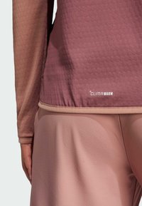 Mörkröd långärmad topp med texturerat mönster, med en beige elastisk fåll och "CLIMAWARM"-logotyp nederst. Mjukt tyg, åtsittande design.