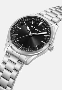 Reloj de acero inoxidable plateado con una esfera negra, marcadores de hora plateados y la palabra "POLICE" exhibida de manera prominente. Presenta una pulsera texturizada.