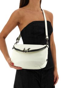 Borsa a tracolla in pelle bianca con chiusura a zip, caratterizzata da una forma curva e dettagli in metallo. Tracolla regolabile e texture liscia.