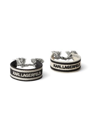 Two woven bracelets in black and cream, featuring "KARL LAGERFELD" text. Each has decorative tassels at the ends and a smooth texture.