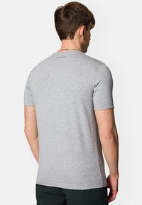 Szara koszulka z krótkim rękawem, wykonana z miękkiej bawełny, z okrągłym dekoltem i małym logo marki na górnej części pleców. Gładka textura.