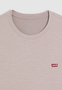 Lichtbeige crewneck t-shirt van zachte stof, met een klein rood Levi's logo op de voorkant, met een gladde textuur en een minimaal ontwerp.