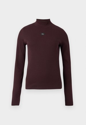 Top bordeaux a maniche lunghe con collo alto, dalla texture a coste e con una piccola toppa con il logo sul petto. Vestibilità aderente, tessuto dall'aspetto liscio.