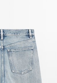 Jeans in denim blu chiaro con un classico design a cinque tasche, dotati di una tasca posteriore rettangolare e dettagli di cucitura visibili.