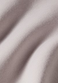 Rekbare tricot stof in een zachte mauve tint, met een geribbelde textuur en subtiele variaties in licht en schaduw. Glad, lichtgewicht en flexibel.