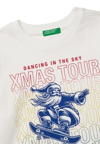 Bílý bavlněný tričko s grafikou Santy na skateboardu. Text zní "DANCING IN THE SKY XMAS TOUR" v červených a žlutých odstínech.