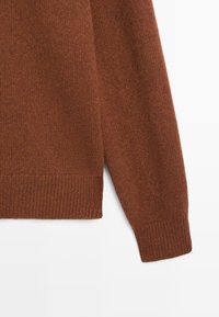 Bruine gebreide trui met lange mouwen, geribbelde manchetten en zoom, op een witte achtergrond.