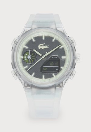Relógio transparente com um mostrador redondo, textura preta e detalhes luminescentes, ecrã digital e bracelete de silicone transparente.