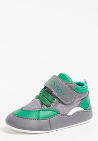 Szare i zielone dziecięce sneakersy o teksturowanym wykończeniu, z rzepem, sznurowanym detalem i białą gumową podeszwą.