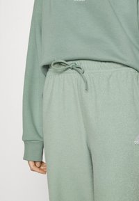 Grön sweatshirt och matchande joggers i mjukt tyg, med dragsko i midjan, ribbade muddar och vit logotypdetalj.