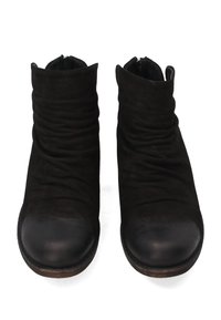 Para czarnych zamszowych botków za kostkę z zaokrąglonymi noskami, teksturowanymi zagięciami i brązowymi drewnianymi podeszwami, widocznych z przodu na białym tle.