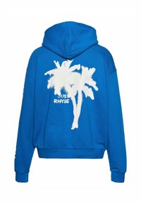Sudadera azul con una textura suave, con un gráfico de una palmera blanca y el texto "JUST RHYSE" debajo. Con capucha y un diseño de corte relajado.