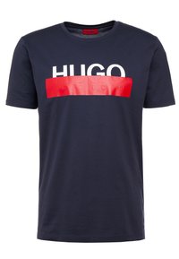 T-paita, jonka väri on tummansininen, valmistettu puuvillasta ja jossa on lyhyet hihat. T-paidassa on valkoinen "HUGO"-logo ja punainen korosteleveys, jossa on kohokuvioitu logo-kuvio.