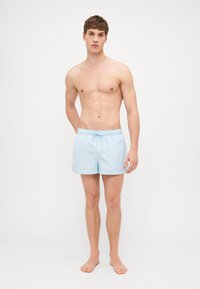 Helle blaue Badehose aus einem leichten Stoff, mit einem elastischen Bund und Kordelzug, seitlichen Taschen und einer lockeren Passform.
