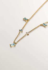 Collar de cadena dorada con cristales rectangulares azules y transparentes, con cinco gemas engastadas en configuraciones elegantes y minimalistas.