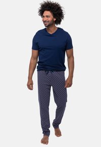 Marineblauw T-shirt met korte mouwen, gecombineerd met gestreepte pyjamabroek met een donkere basis en gekleurde stippen, elastische tailleband, relaxte pasvorm.