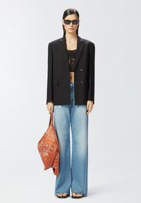 Crni krojeni sako preko čipkastog topa s kratkim rukavima, svijetloplave široke traperice i torba s narančastim uzorkom, uz crne pravokutne sunčane naočale.