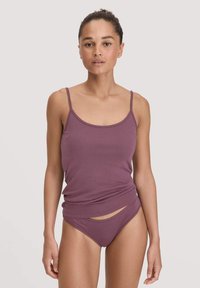 Lila Trägershirt mit dünnen Trägern und abgerundetem Saum, kombiniert mit passenden Bikiniunterteilen, die einen modernen Schnitt und seitliche Schlitze aufweisen.