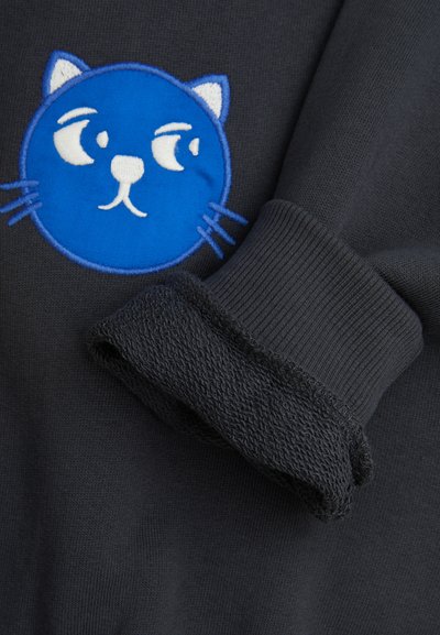 Maglione nero con ricamo di una faccia di gatto blu, caratterizzato da un collo rotondo e polsini a costine con una finitura texturizzata.