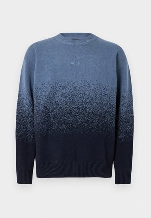 Stickad crewneck-tröja i gradientblå nyanser, som övergår från ljus till mörk, med subtila fläckiga detaljer och ribbad fåll.