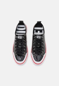 Sneakers in pelle verniciata nera con suole bianche e accenti rossi. Presentano lacci neri, un sottopiede stampato e occhielli metallici per una maggiore durevolezza.